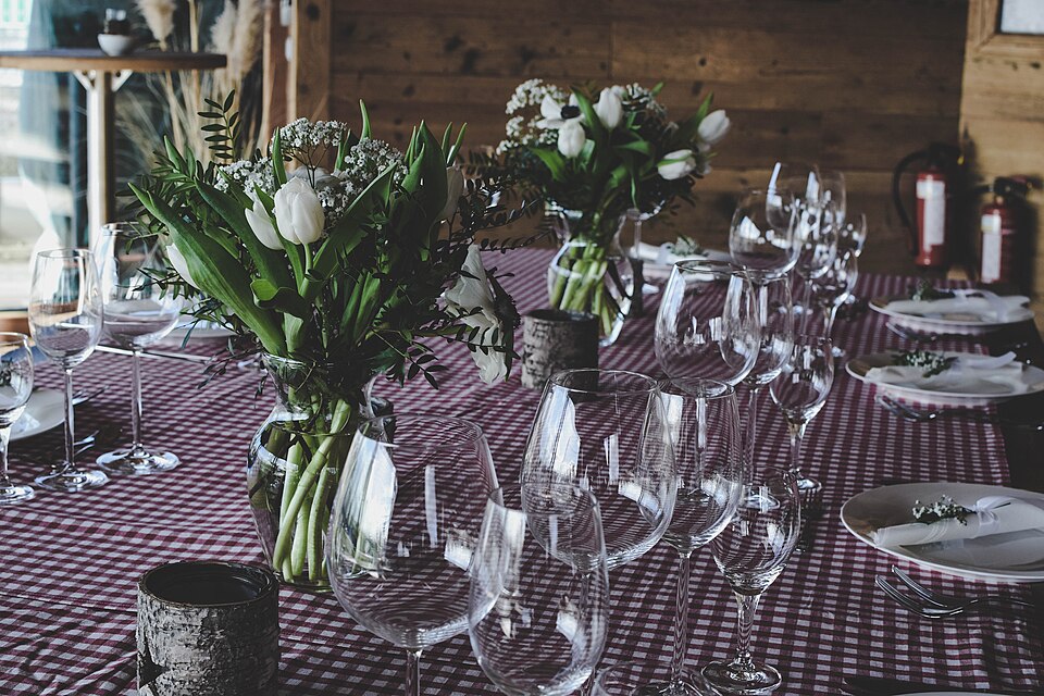 Mesa longa preparada para um evento, com louça e flores
